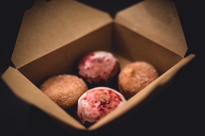 棕色纸板箱中四个甜甜圈的选择性聚焦摄影